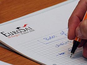 Osoba robiąca notatki na papierze z logo EUROSAI