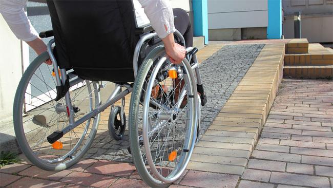 A person on the wheelchair going up the wheelchair ramp