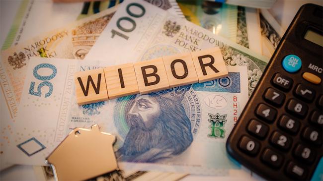 Napis WIBOR z liter gry Scrabble ułożony na banknotach, obok kalkulator