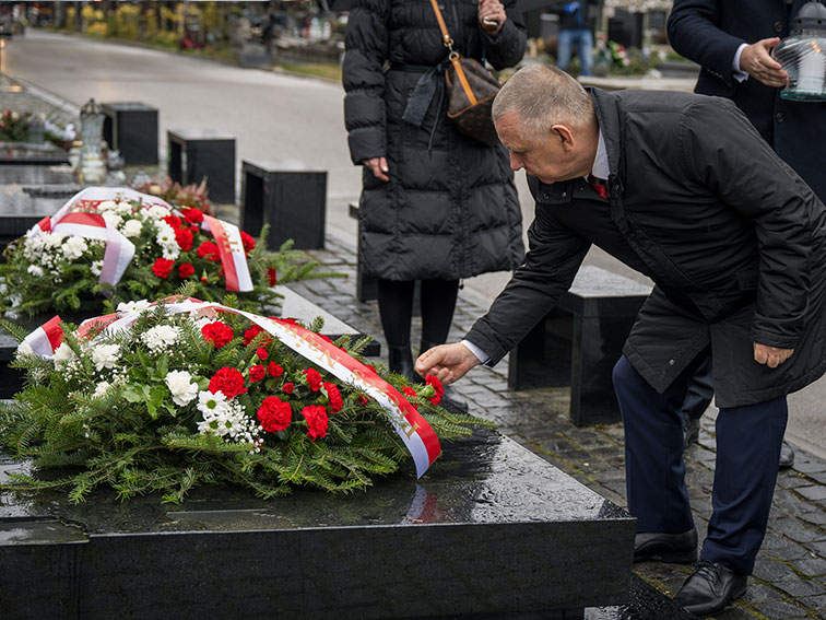 Prezes NIK Marian Banaś poprawia szarfę wieńca złożonego na grobie Władysława Stasiaka